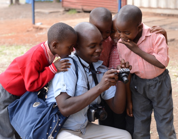 Justus looking at photos with the children near Kibera Paper